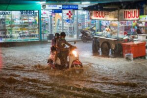 Heavy rain and flooding in street with motor bike and child passenger