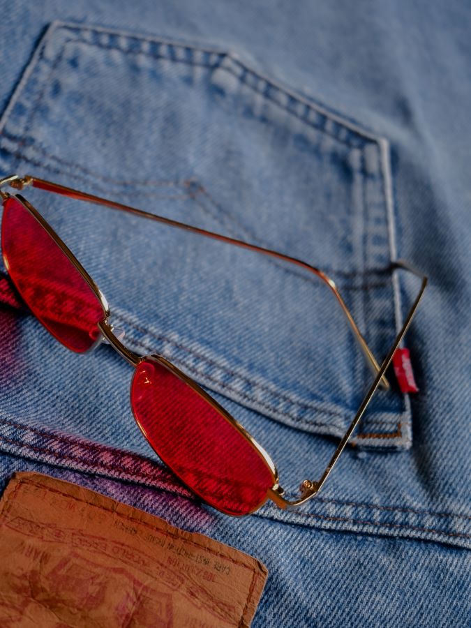 Pair of faded levi's with red sunglasses laying on them