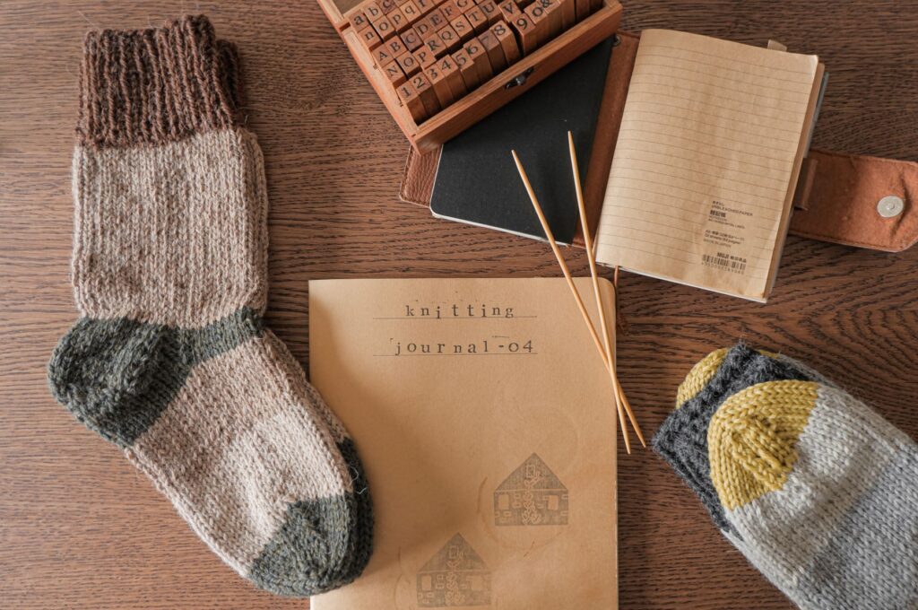 Knitting notebook and knitting needles with pair of knit wool socks.