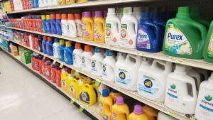 The laundry detergent aisle of a small grocery store, that shows rows and rows of plastic jugs holding liquid laundry detergent.